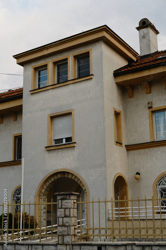 Obraz premium Elegant architecture of a residential house with arched doorway, yellow details and white walls