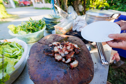 A man grills pork in a crispy, fragrant pot at a party. The crispy pork chops are a popular dish in Thailand.