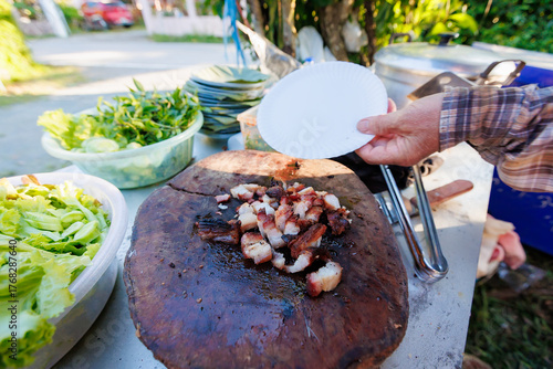 A man grills pork in a crispy, fragrant pot at a party. The crispy pork chops are a popular dish in Thailand.