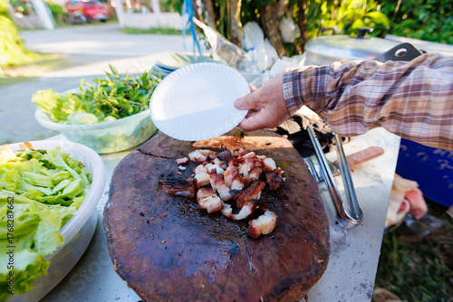 A man grills pork in a crispy, fragrant pot at a party. The crispy pork chops are a popular dish in Thailand.