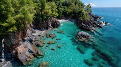 Drone view of a tropical island coastline with vibrant turquoise clear water lush green trees and rocky shores under bright daylight.