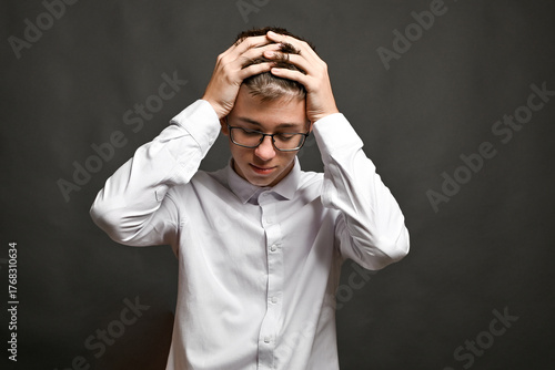 Behang Young man holding head in stress with closed eyes, expressing headache, tension, regret, or overwhelming pressure