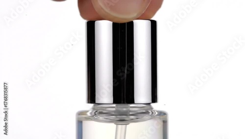 Hand removing silver cap from clear spray bottle. Perfume, cologne, or cosmetic product packaging. Isolated on white.