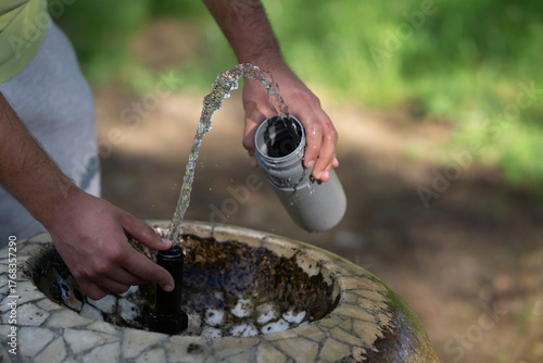 Close up of male hands filling a bottle with drinking water in a public drinking fountain