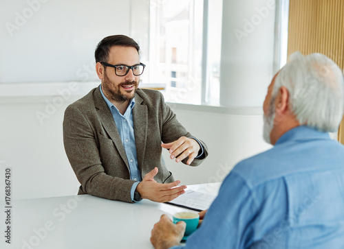 Konstfotografi Two businessman having a meeting and lookung at a document or a contract agreement in the office, or a senior mad pensioner supported ny a real estate agent or advisor or a doctor