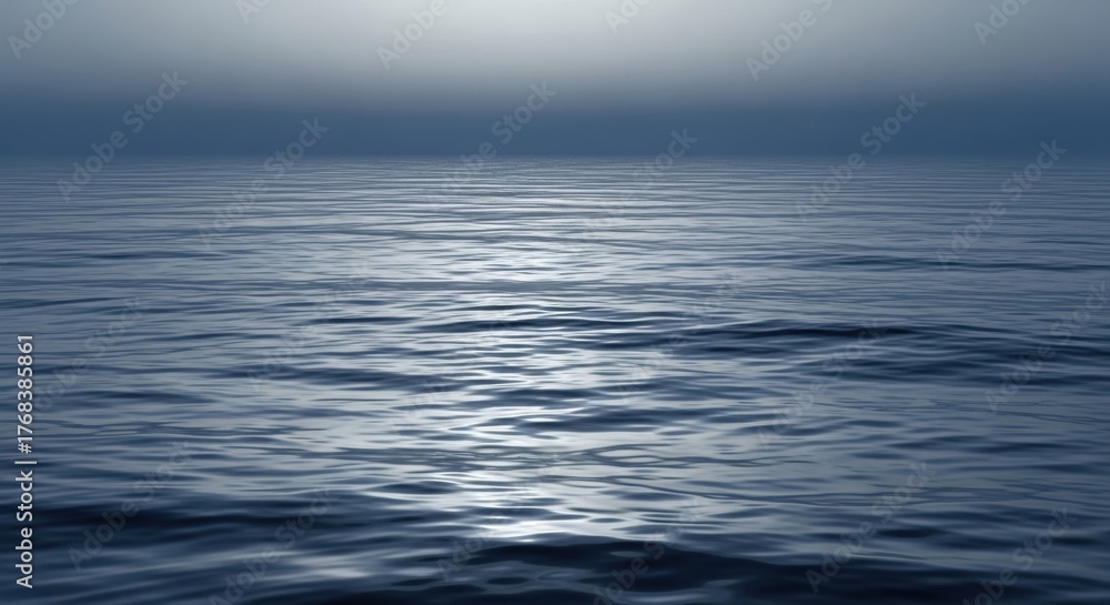 Obraz premium Calm and serene ocean waves ripple gently under a hazy blue sky, creating a tranquil and peaceful seascape.