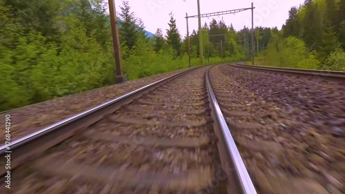 A time lapse low angle view of train tracks riding across the kandertal valley in switzerland on a cloudy day