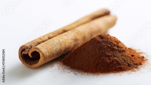 Close up of cinnamon sticks and a pile of ground cinnamon spice on a white background
