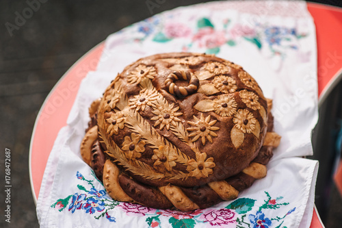 A close-up photo of a Ukrainian decorated loaf of bread on an embroidered towel.
