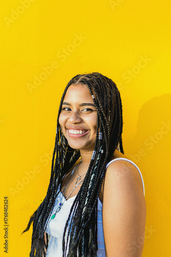 Portrait of a beautiful black woman with braids smiling with a yellow background