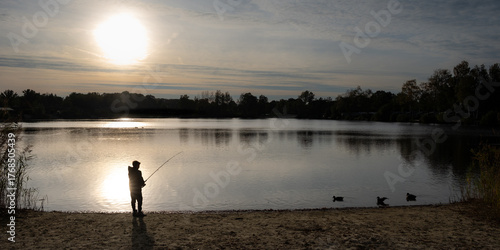 Stimmungsvolle Silhouette eines Anglers am See bei Sonnenuntergang