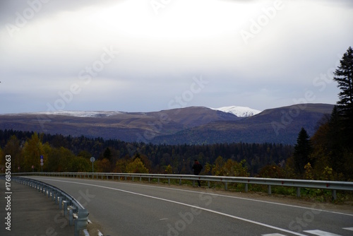 Asphalt road in the foreground. There are forests and mountains in the far east. Evening twilight.