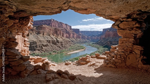 Canyon river vista framed by ancient cave opening and towering red sandstone cliffs