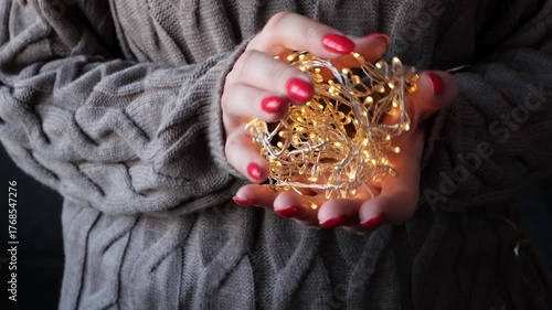 Warm hands cradle glowing fairy lights in cozy knit sweater setting