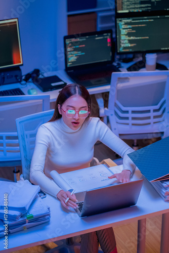 Asian female smart programmer works late night office coding deep learning AI models, training neural networks with intense concentration and focus, dedicating overtime hours alone to machine learning