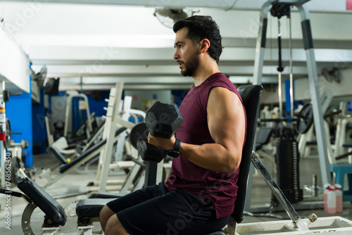 Fotografie Active man doing bicep curl workout with dumbbell in gym