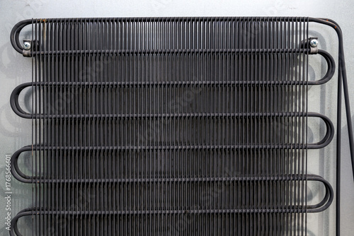 Metal grid condenser coils on refrigerator back panel, showing industrial structure and functional cooling system detail