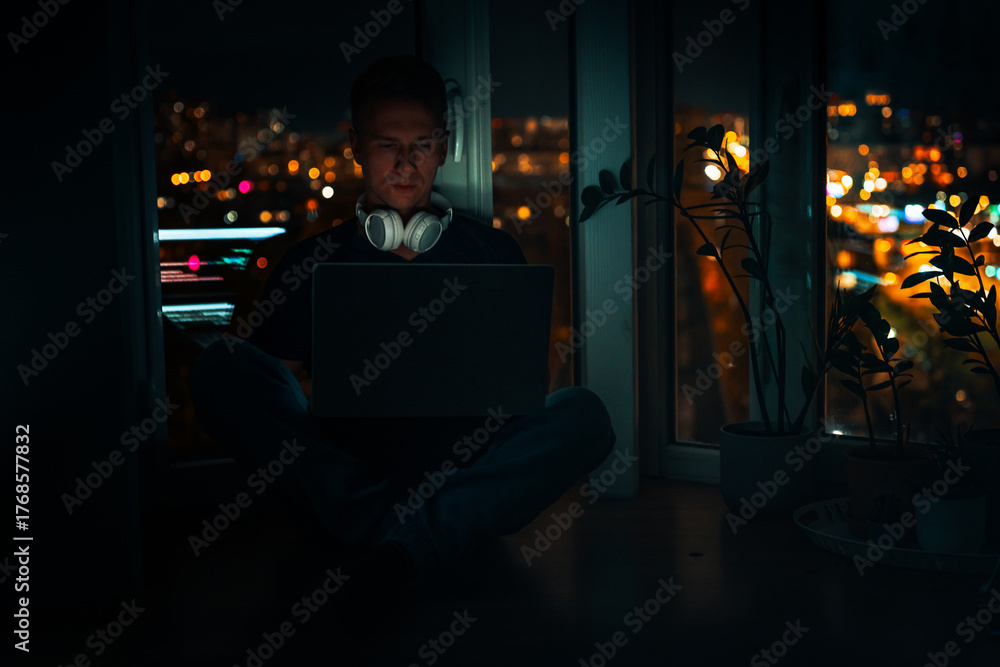 Obraz premium A young male developer is programming a code script late at night with beautiful city lights at night.