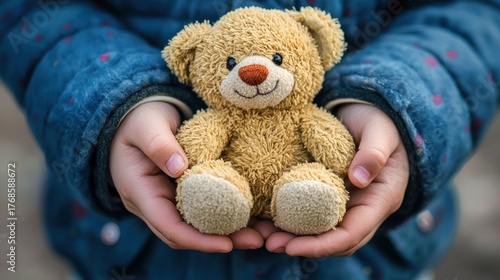 A close-up of an orphan childâ€™s hands holding a small stuffed animal tightly.