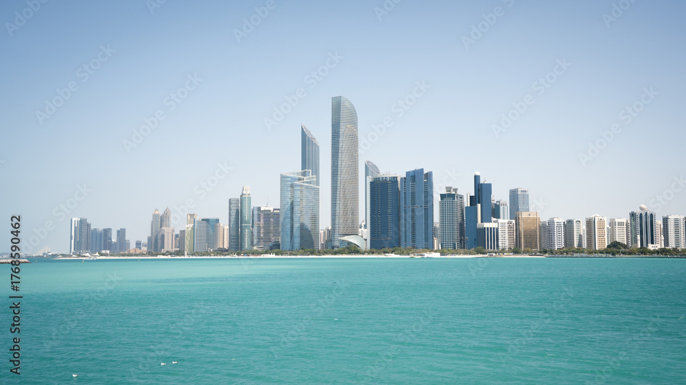 Fototapeta premium Coastal cityscape with high rise buildings and azure waters in foreground, United Arab Emirates