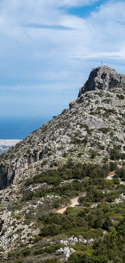 Naklejka premium Rocky mountain peak with cross overlooking coastal landscape, Crete