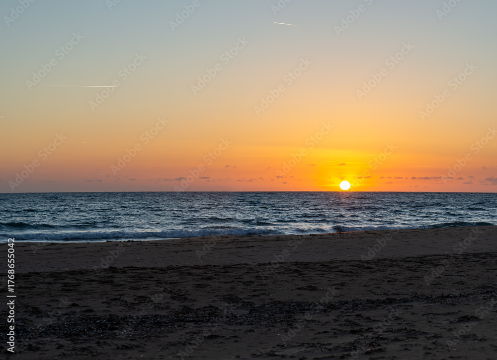 Obraz premium Peaceful sunset over calm sea and sandy beach in Crete