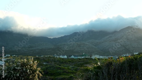 Mountain landscape with low clouds over coastal houses in soft morning light creating cinematic nature atmosphere
