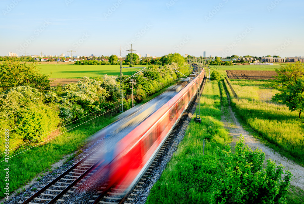 Fototapeta premium Fast train in green landscape - regional connection between city and countryside - symbol and concept of public transport, commuters, rush hour and Intercity train travel - Munich, Germany
