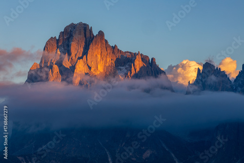 sunset on Alpe di Siusi in the Italian Dolomites - the sun shines through the clouds on a rocky alpine peak