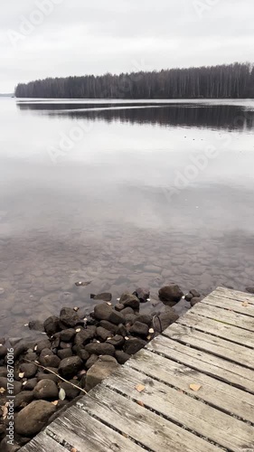 Serene lake view with wooden pier and lake. Calm autumn atmosphere. Vertical video