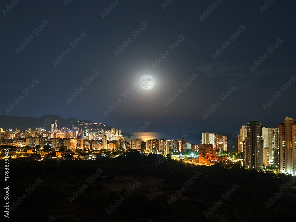 Fototapeta premium A beautifully serene night cityscape featuring a stunning full moon over the vibrant urban skyline
