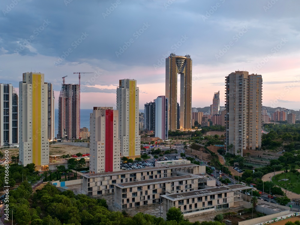 Fototapeta premium soft evening light over urban development, city skyline with ongoing construction under sunset glow