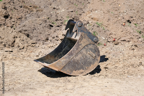 Konzept Erdarbeiten und Landschaftsbau: Seitenansicht einer großen Bagger Schaufel auf einer Baustelle vor Aushub mit viel Freiraum für Textgestaltung
