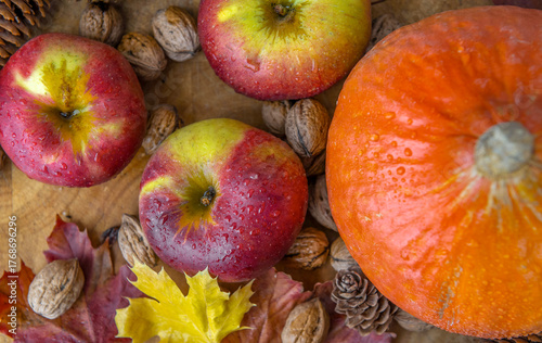 top view on bright red apples covered by drops and orange pumpkin walnuts and...