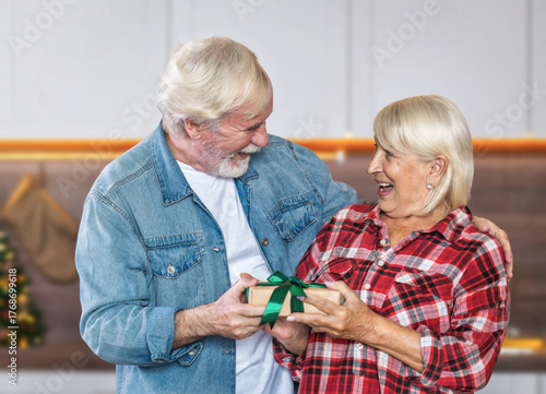 Happy seniors exchanging holiday gift at home
