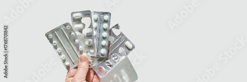 Hand holding blister packs of pills on white background for medical and pharmaceutical concepts.