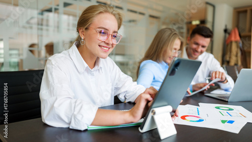 Team members collaborating on a project in a modern office space with digital devices