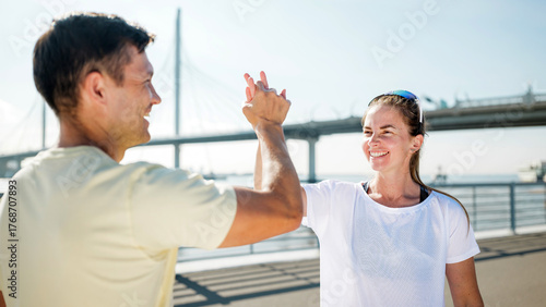 Quadro su tela Happy friends celebrating fitness at a riverside park during morning exercise se