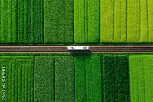 Modern high speed train, Train travels through vibrant green fields from an aerial perspective.