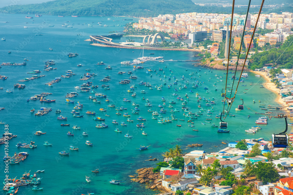 Fototapeta premium Aerial view of An Thoi harbor with coastal fishermen village, fishing boats, turquoise sea and modern cable car ride on Phu Quoc island, Vietnam. Modern Hon Thom cable car cabin