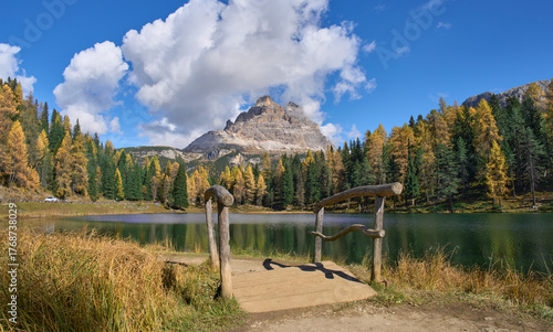 The wooden bridge next to Lago d’Antorno, lake of Antorno. Autumn landscape with small alpine lake, yellow and green trees and a direct view of the most famous Dolomites landmark, Tre Cime di Lavaredo