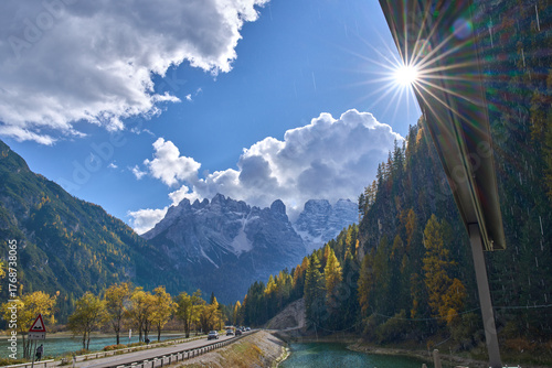 Autumn landscape around Lago di Landro, Dürrensee in Tre Cime di Lavaredo park. Turquoise lake. A view on Cristallo Group and Ampezzo Dolomites. Rain and rays radiating from the sun. Cumulus clouds.