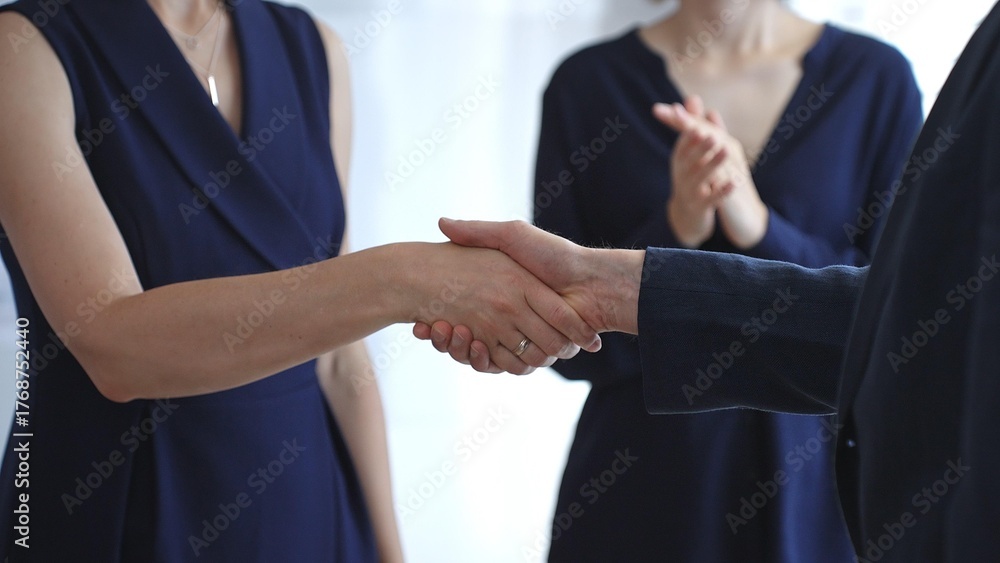 Fototapeta premium Business executives shaking hands during a successful corporate meeting, finalizing an important deal while a colleague claps in approval, symbolizing strong teamwork and growing success