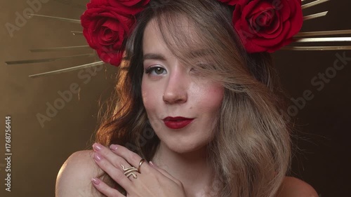 Horizontal video. Young adult white beauty woman with DIY golden halo crown and rose on head, red lips, make up, red dress, gold bracer, shoulder pad. Magic holy fantasy lady on fog, smoke background