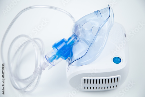 Top view of the breathing blue mask of the inhaler lies on the device on a white background. The concept of treating respiratory diseases, lung diseases, prevention and self-care. High quality photo