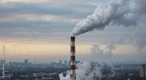 Industrial smokestack emitting smoke over city skyline at sunset - Concept of Power saving  
