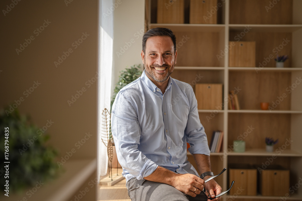 Fototapeta premium Smiling man holding glasses at home office