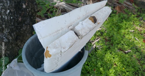 Half broken surfboard in trash bucket. 