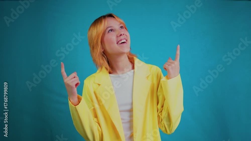 Excited young woman pointing upwards with index fingers at copy space