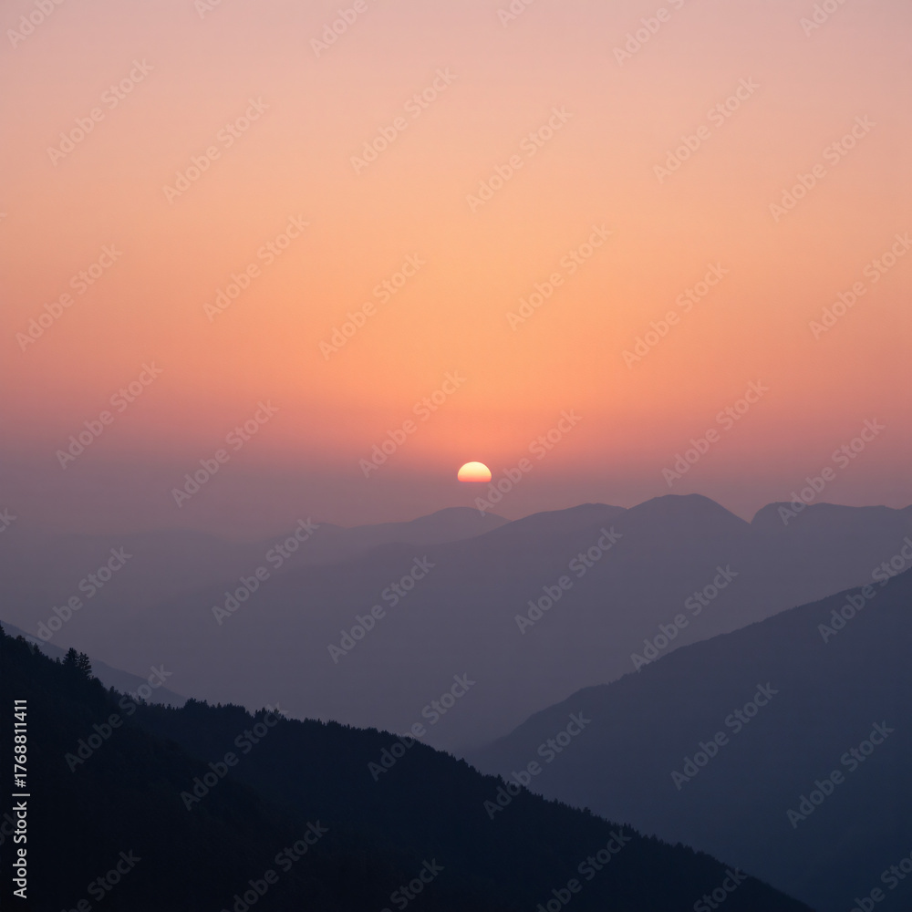 Fototapeta premium Sunrise over misty mountain range, warm orange‑pink sky